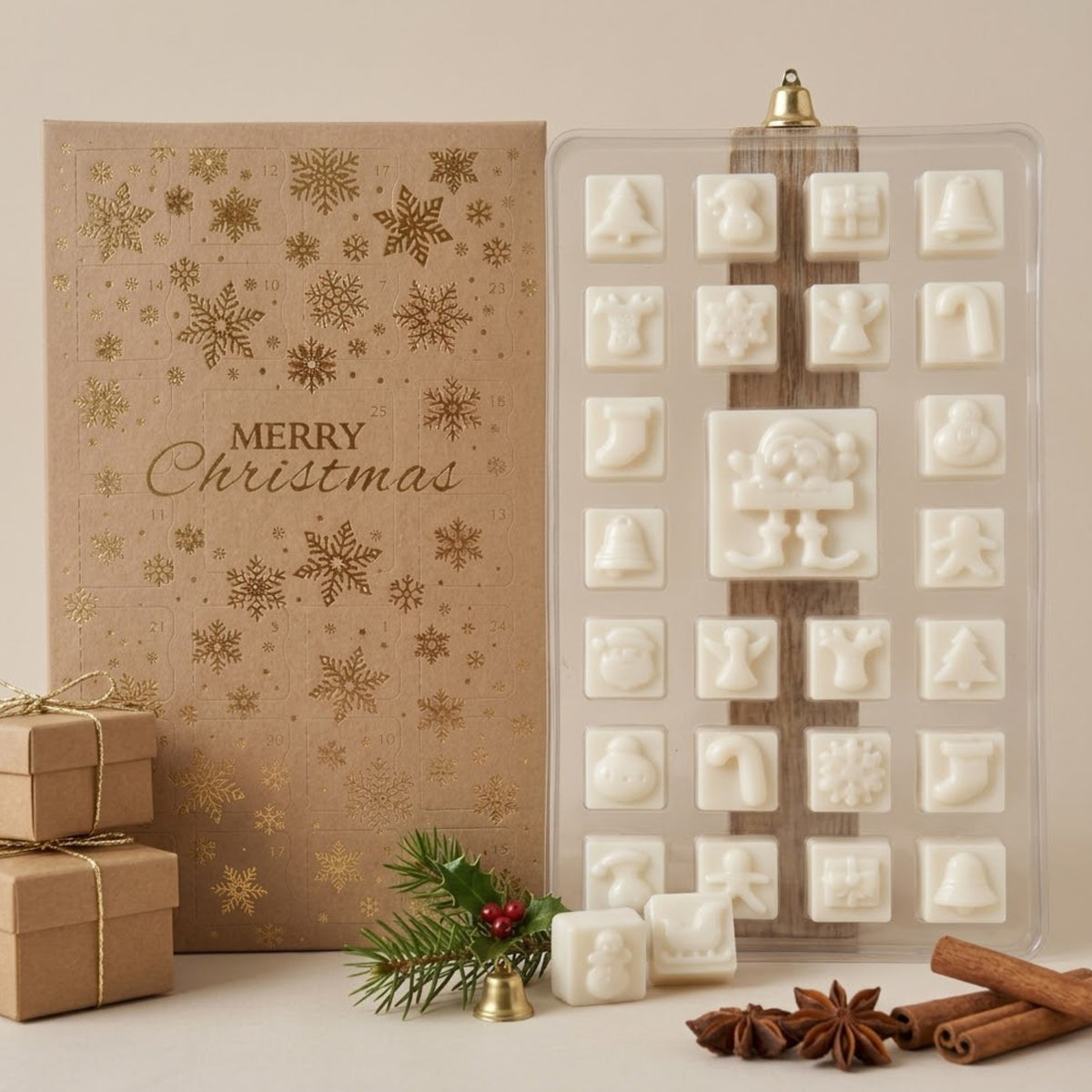 A holiday-themed product display featuring a clear plastic tray filled with white soy wax melt shaped like Christmas icons, next to a kraft paper gift box with gold snowflakes and 'Merry Christmas' text. Decorative elements including pine branches, a small gold bell, cinnamon sticks, and star anise are arranged at the bottom on a light beige surface.