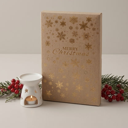 A rectangular Kraft Christmas soy wax advent calender box with gold foil snowflakes and the words 'Merry Christmas' on the front, styled on a light surface with a white wax melter and red berries.